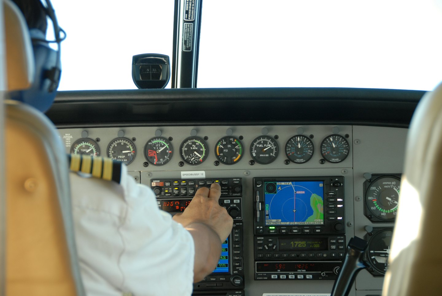 Pilotenhand auf Flugzeugsteuerung mit Anzeigen und Sonnenlicht.