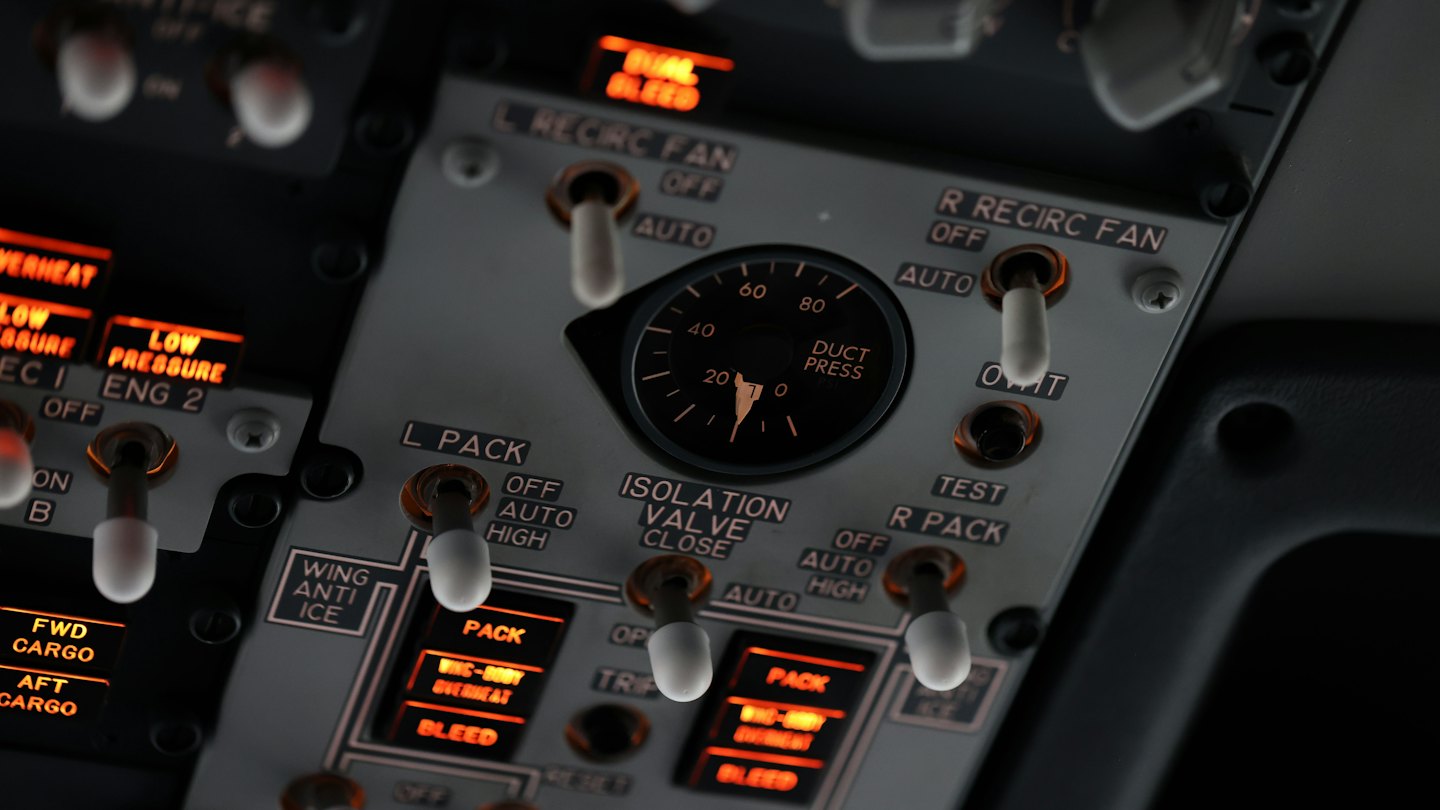 Beleuchtetes Flugzeugcockpit-Panel mit zahlreichen Kippschaltern und Reglern.