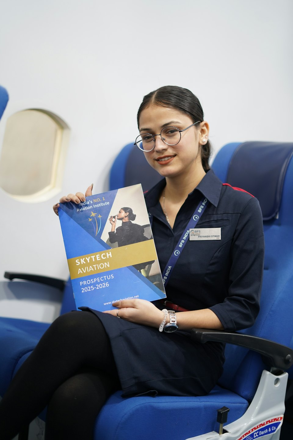 Pilotin in Uniform hält Skytech Aviation Broschüre auf einem Flugzeugsitz.