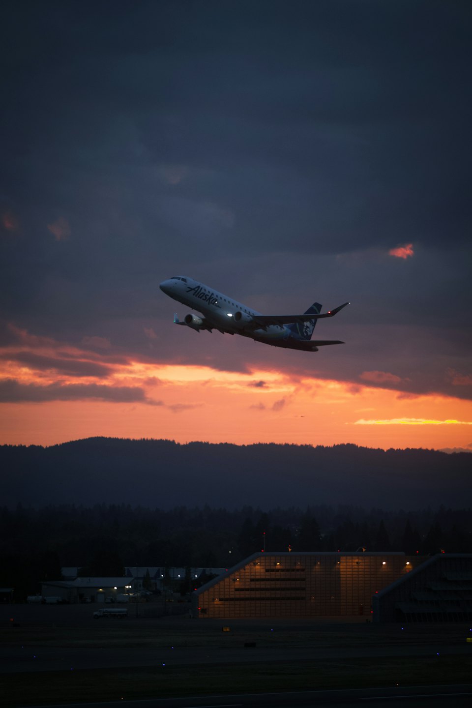 Flugzeug steigt in einen lebendigen Sonnenuntergangshimmel auf.